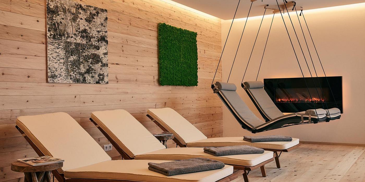 Raum der Stille im NaturSpa des Hotel Birkenhof Oberstaufen mit Liegen, schwebenden Relaxliegen und modernem Kamin.
